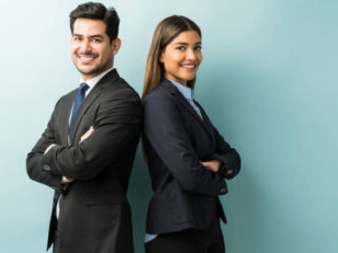 Young business professionals, a man and woman, back-to-back, smiling.