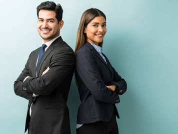 Young business professionals, a man and woman, back-to-back, smiling.