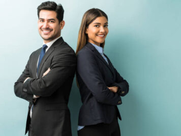 Young business professionals, a man and woman, back-to-back, smiling.