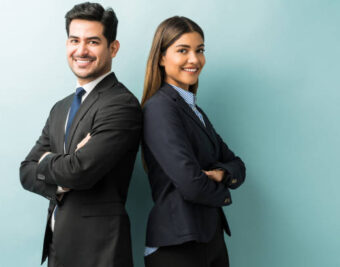 Young business professionals, a man and woman, back-to-back, smiling.