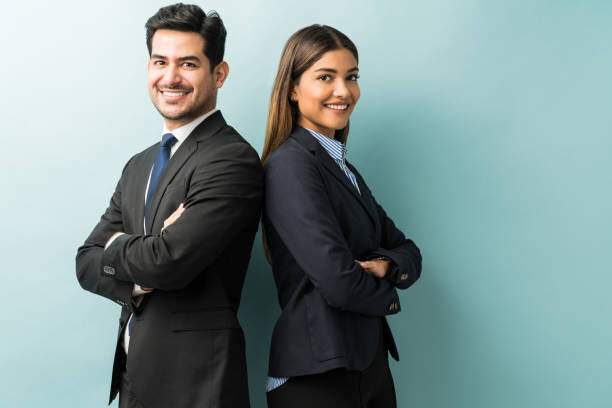 Young business professionals, a man and woman, back-to-back, smiling.